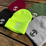 On a wooden table, five colorways of woven Oaklandish logo cuffed beanies (black, grey, green, burgundy, and fluorescent yellow).