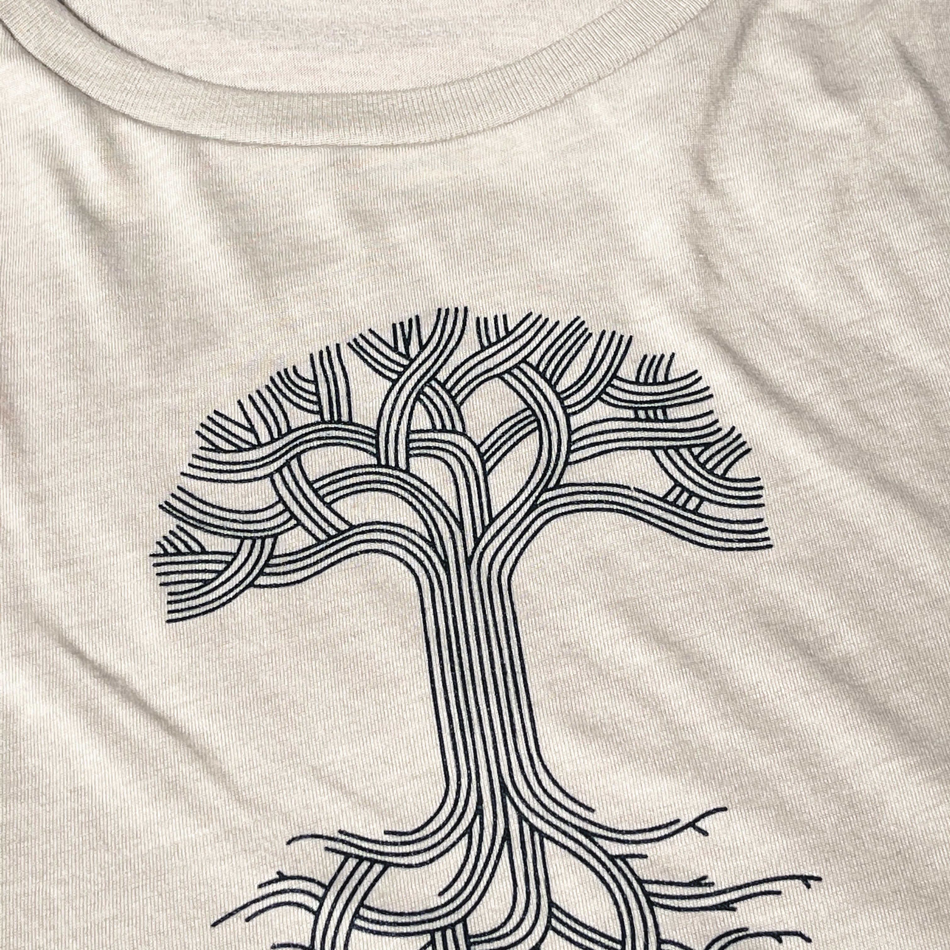 Close up of black classic Oaklandish tree logo and wordmark on chest of a heather dust women’s cut tank top.
