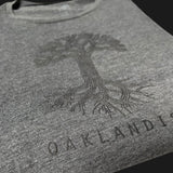 Close-up black classic Oaklandish tree logo and wordmark on chest of a grey women’s cut tank top.