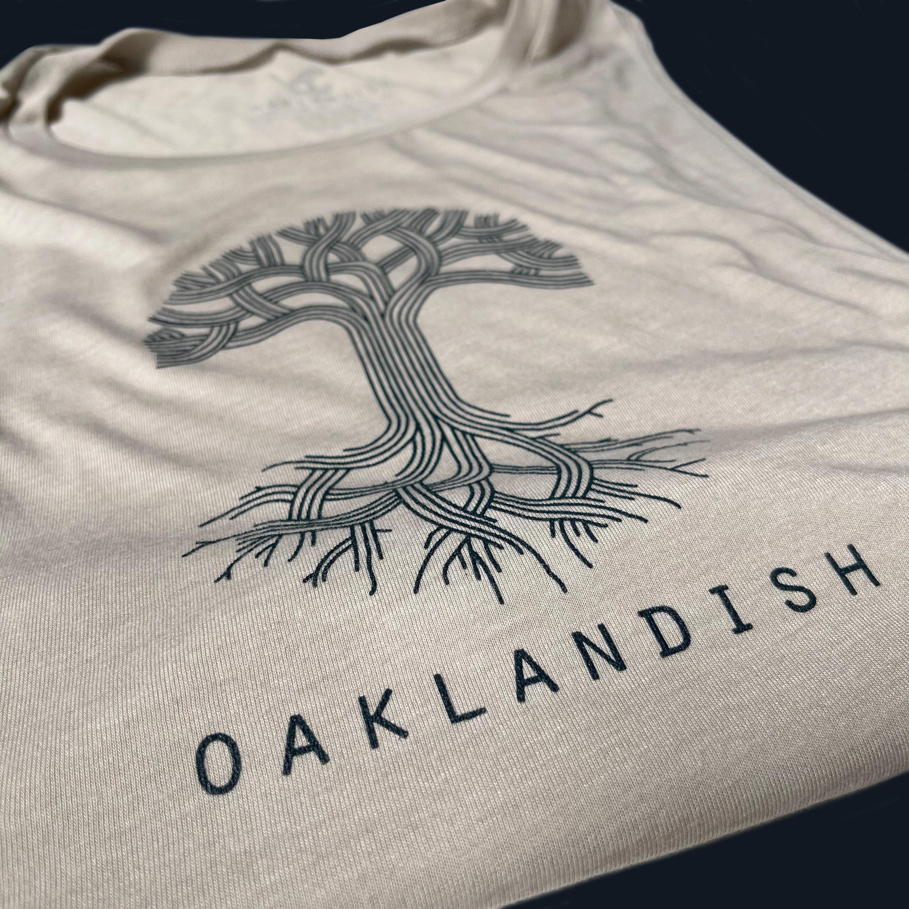 Close up of black classic Oaklandish tree logo and wordmark on chest of a heather dust women’s cut tank top.