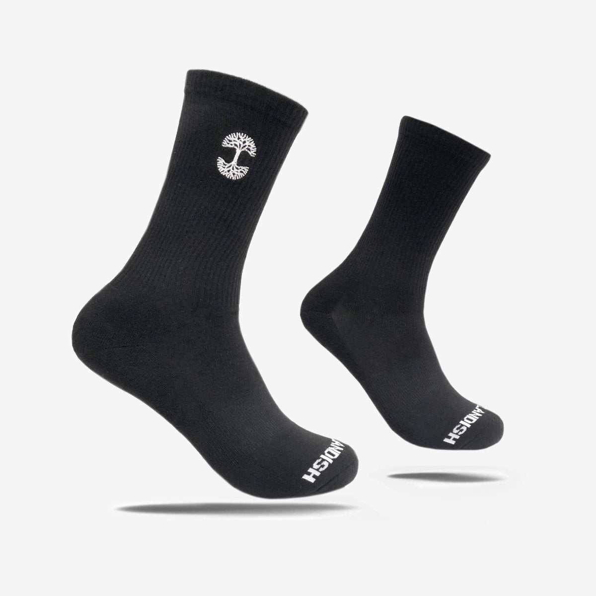 A pair of black Embroidered Logo Socks is shown against a white background. The Oaklandish logo, which resembles a tree, is featured on the outer side near the top. In adult sizes, the toe area displays "Oaklandish" in white lettering. The socks are ribbed at the ankle with a smooth texture on the foot.