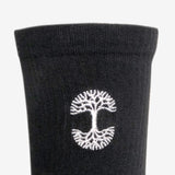 Close up of white embroidered Oaklandish logo at the top of black men’s crew socks.