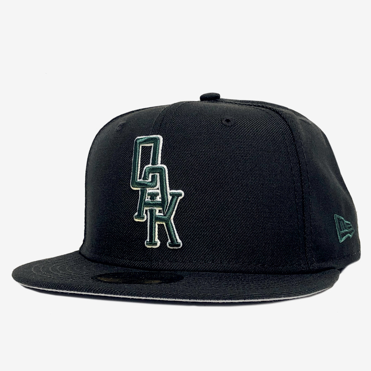 Black New Era cap with a green and white embroidered OAK wordmark on the crown. 