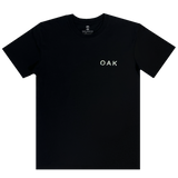 Front view of a black t-shirt with OAK wordmark on the right chest in white puff ink print.
