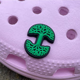Green and black Oaklandish tree logo shoe charm on a pink croc shoe.