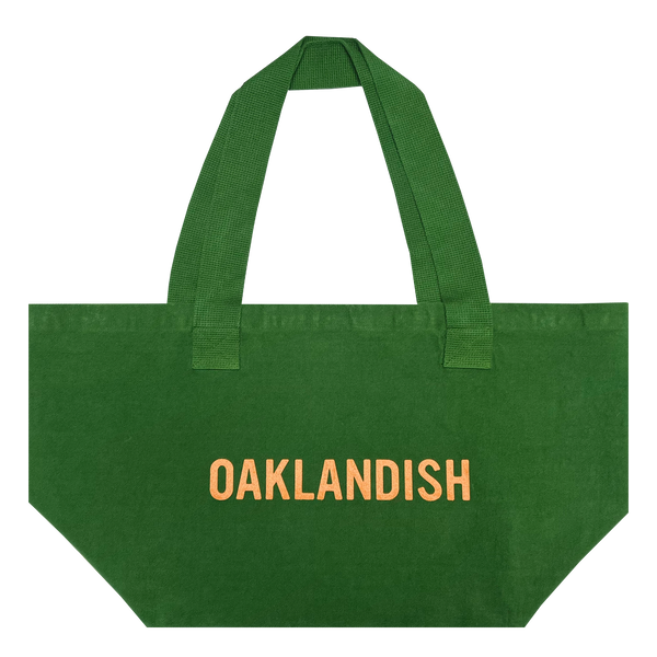 Front view of vintage green shopping tote with Oaklandish wordmark in creme ink creme ink.