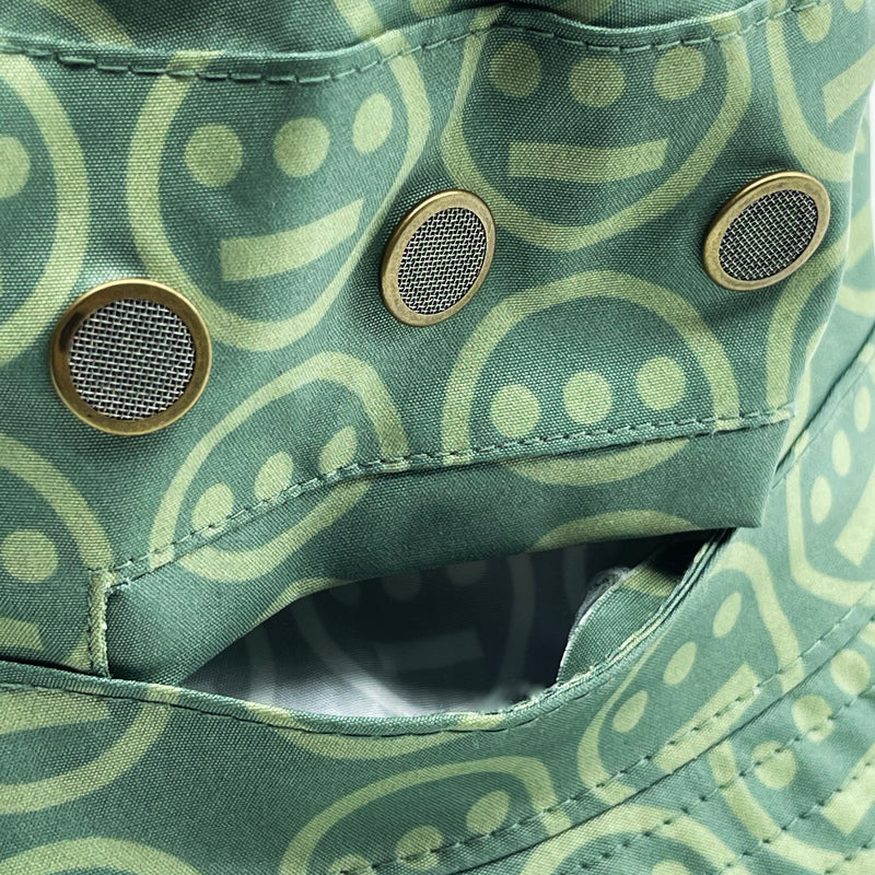 Close-up of pocket on the green side of a reversible bucket hat with light green Hieroglyphics hip-hop logo on repeat. 