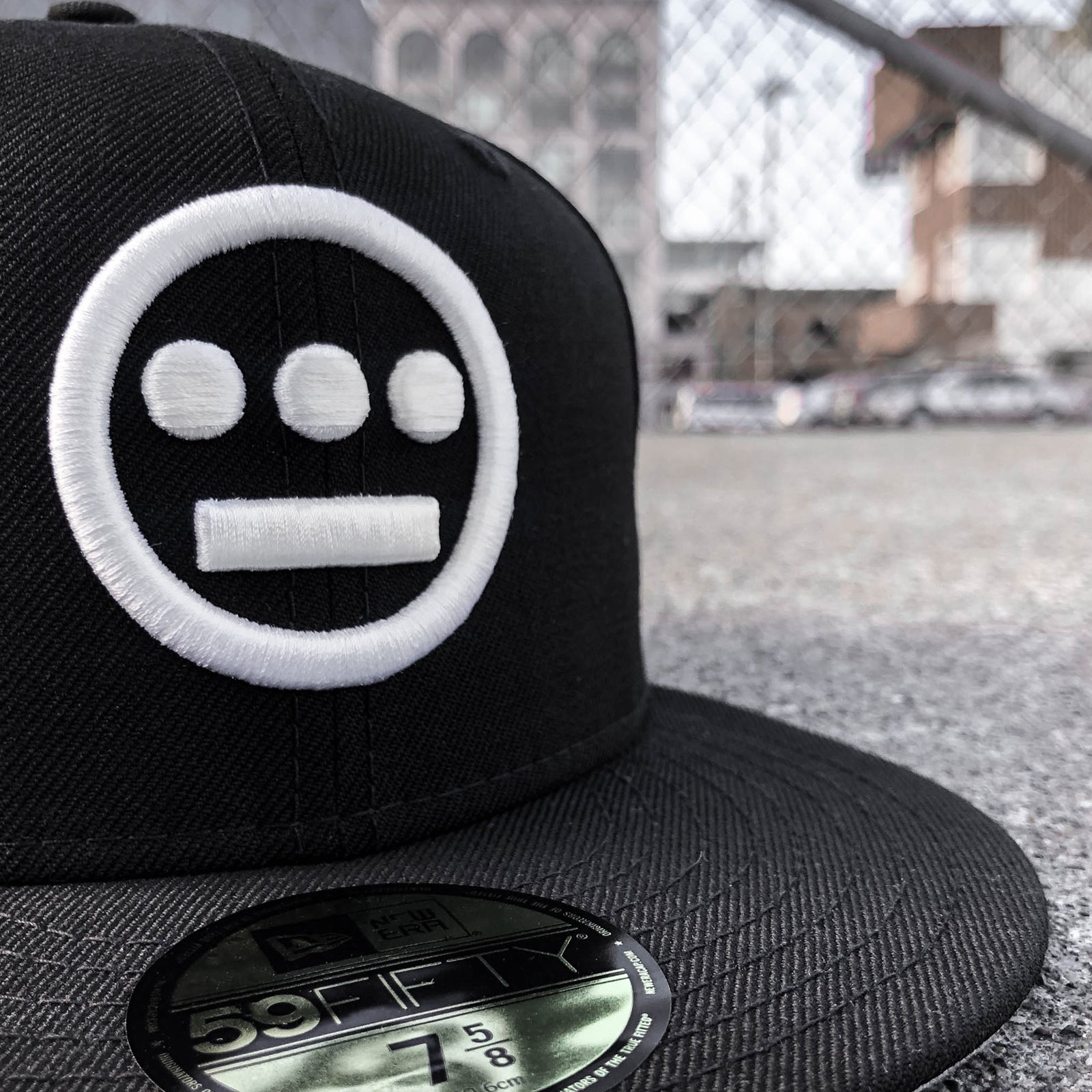 Close-up of embroidered white Hieroglyphics hip-hop logo on a black New Era cap.