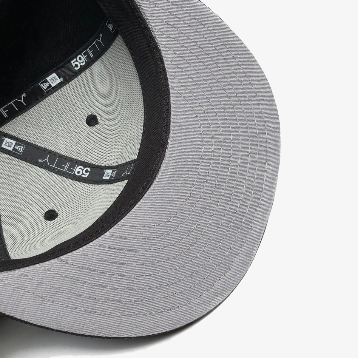 The grey underside of the bill on a New Era black cap.