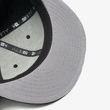 The grey underside of the bill on a New Era black cap.