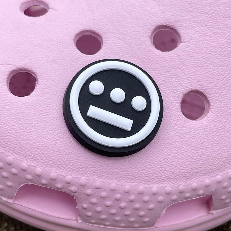 Shoe charm featuring round Hieroglyphics logo in black and white on pink croc clog.