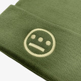 Close-up of embroidered Hieroglyphics hip hop logo on front cuff of a olive green cuffed beanie.