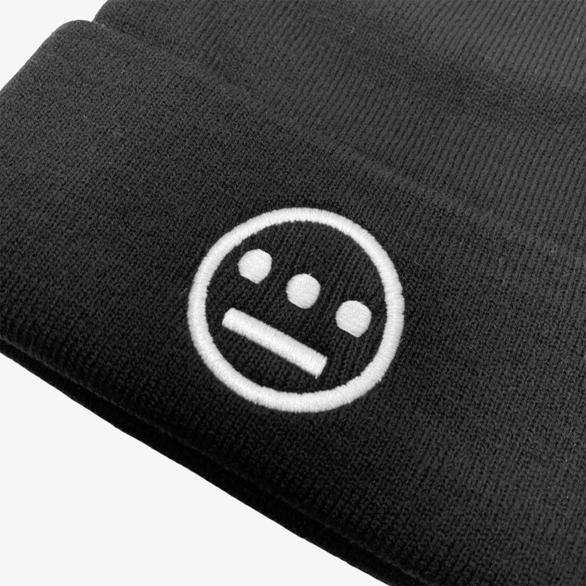 Close-up of white embroidered Hieroglyphics hip hop logo on front cuff of a black beanie.