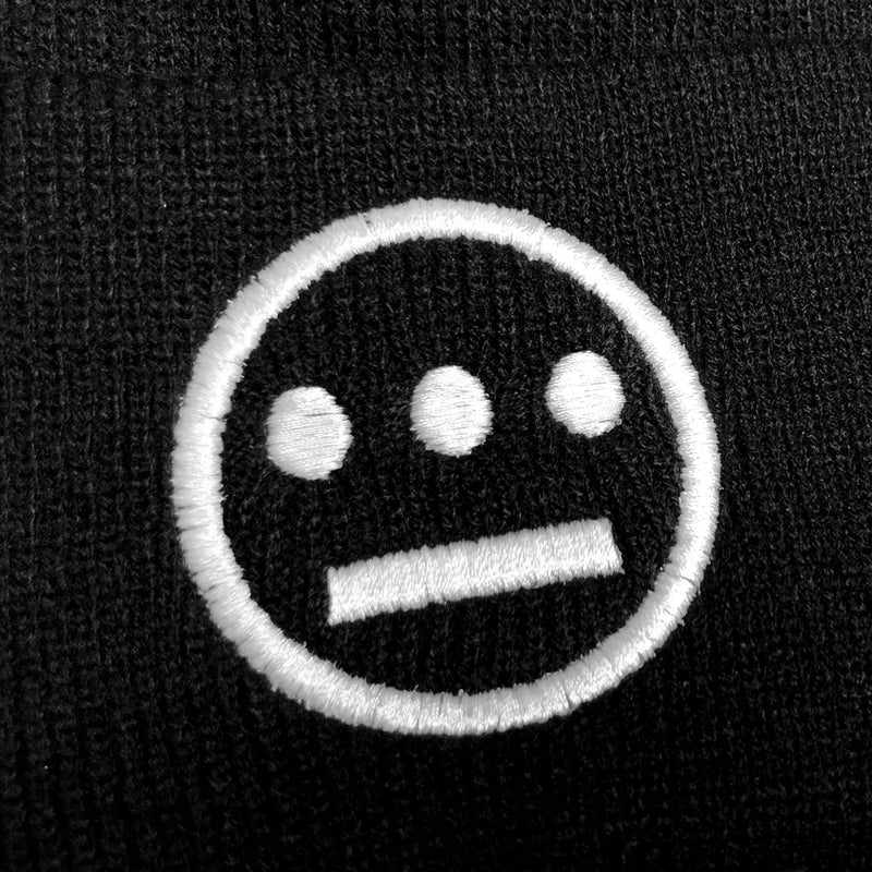 Close-up of embroidered white Hieroglyphics logo on the front cuff of a black cuffed beanie.
