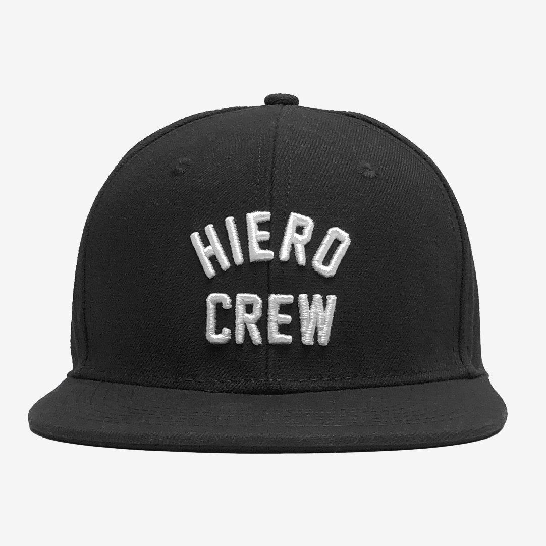 A black Hiero Crew Snapback from Hieroglyphics, featuring a flat brim and bold white uppercase "Hiero Crew" embroidery on the front. The plain light gray background accentuates the design, paying homage to the essence of Hieroglyphics.