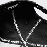 Underside of black dad cap with OAKLANDISH wordmark on inside striping on in crown and Oaklandish logo patch on rim.