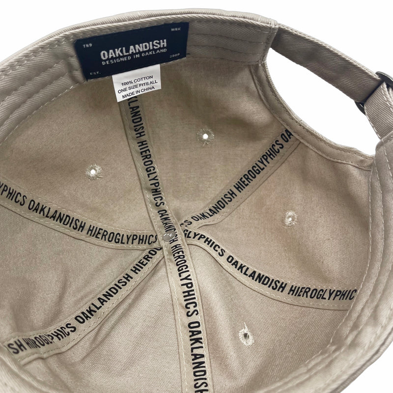 Inside of khaki dad cap crown with ‘OAKLANDISH’ wordmark on black striping and Oaklandish patch.