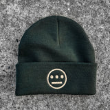 Forest green cuffed beanie with cream Hiero hip-hop crew logo on cuff on asphalt. 