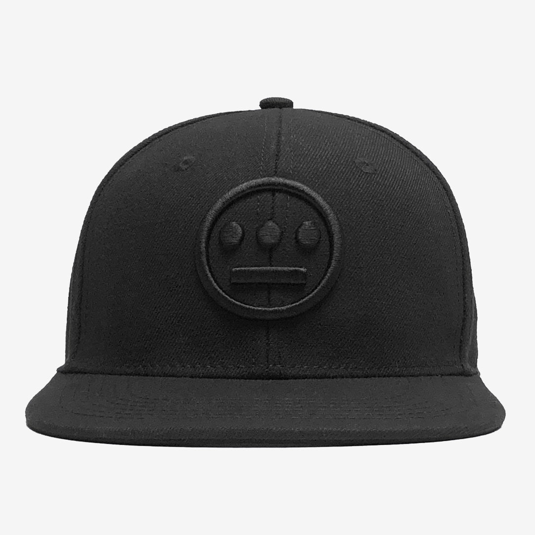 The Hiero Logo Snapback by Hieroglyphics is a black flat-brimmed adjustable snapback cap featuring an embroidered logo on the front. The logo, which resembles a face with two eyes and a nose in a design reminiscent of hieroglyphics with its circle and vertical dots pattern, adds to the cap's clean and simple look, making it perfect for adding a touch of hip hop style to any outfit.