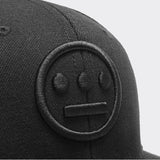 Close-up of embroidered black Hieroglyphics hip-hop logo on a black cap.