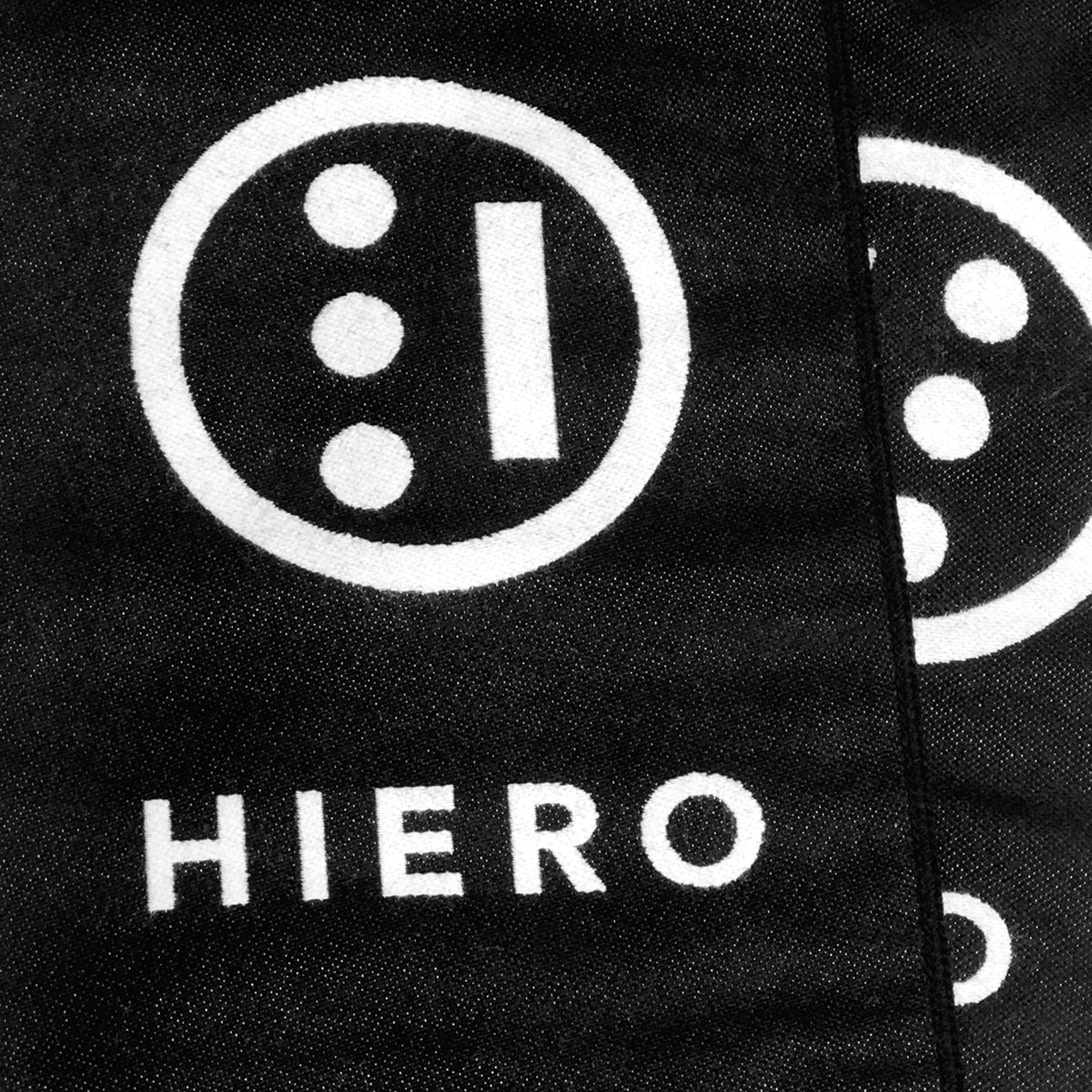 Close up of HIERO hip-hop wordmark and circle logo on a black woven scarf.