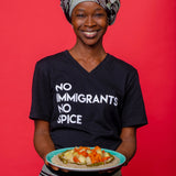 Women wearing a black V-Neck t-shirt with white No Immigrants, No Spice wordmark holding a plate of food. 