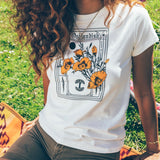 Close-up of a woman wearing a natural color Oaklandish Blossom t-shirt in a park.