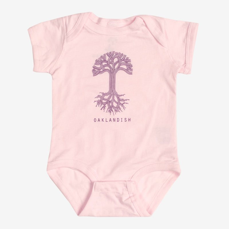 Pink infant one-piece with a purple Oaklandish tree logo and wordmark on the chest.