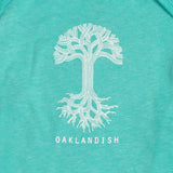Close-up of the white Oaklandish tree logo and wordmark on an emerald green infant one-piece.