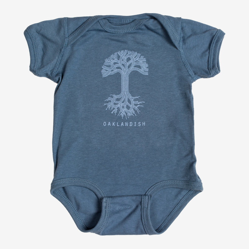 Indigo infant one-piece with a light blue Oaklandish tree logo and wordmark on the chest.