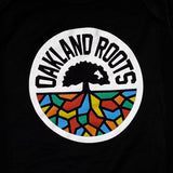 Close-up of full-color Roots SC mosaic logo and wordmark on the chest of a black infant one-piece. 