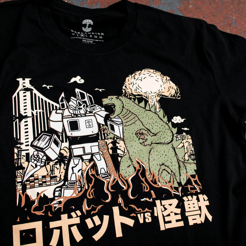 Close-up of graphic depiction of Kaiju vs. Autobart monsters invading Oakland on a black t-shirt laying on asphalt. 