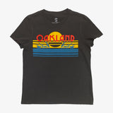 Faded black women’s t-shirt with multi-color license plate design with capital letters spelling out OAKLAND.