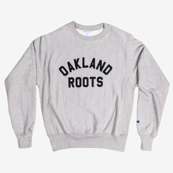 Grey crew sweatshirt with black OAKLAND ROOTS wordmark on the chest.