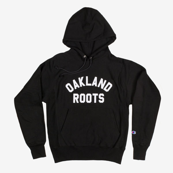The front side of a black pullover hoodie with Oakland Roots wordmark in white capital letters.