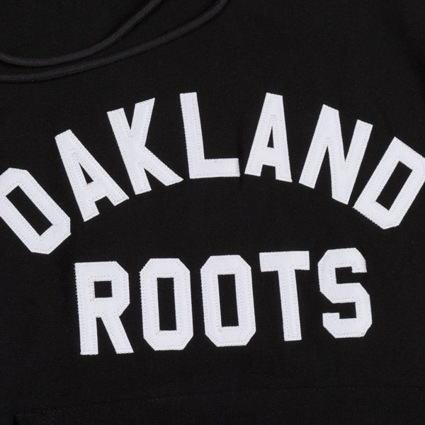 Close up of Oakland Roots wordmark in white capital letters on a black hoodie.