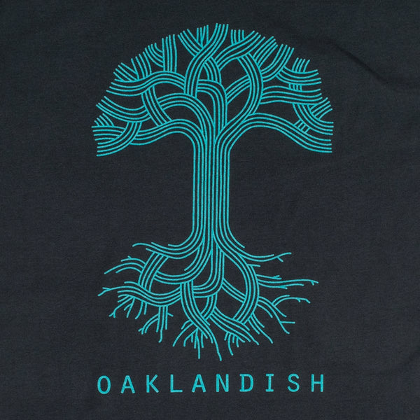 Close-up of large light blue Oaklandish tree logo and wordmark on the chest of a navy t-shirt.