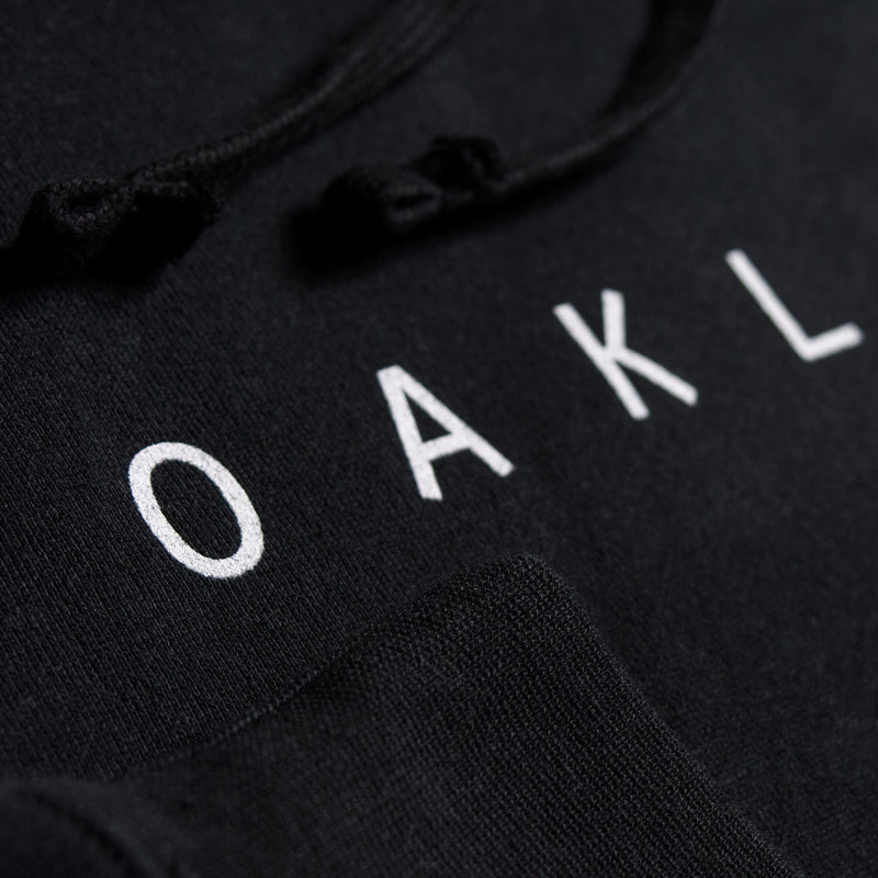 Detailed close-up of OAKLANDISH wordmark on the chest of a black hoodie.