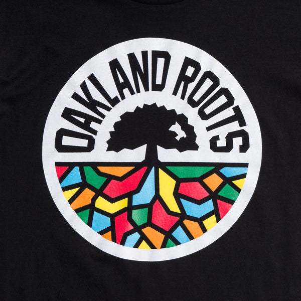 Close up of full-color, round Oakland Roots logo on the chest of a black t-shirt.