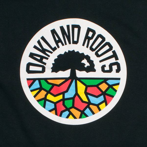 Close-up of ROOTS SC mosaic circle logo on the chest of a black crew neck sweatshirt.