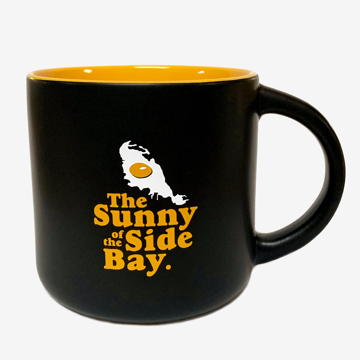 Black ceramic mug with yellow inside with picture of Oakland shaped sunny side up fried egg and words The Sunny Side Of The Bay.