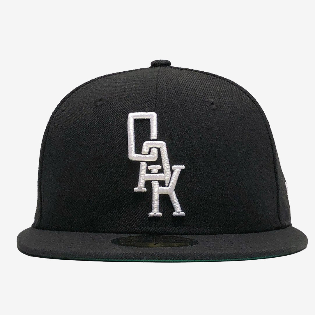 Black New Era cap with white embroidered OAK wordmark on the crown.