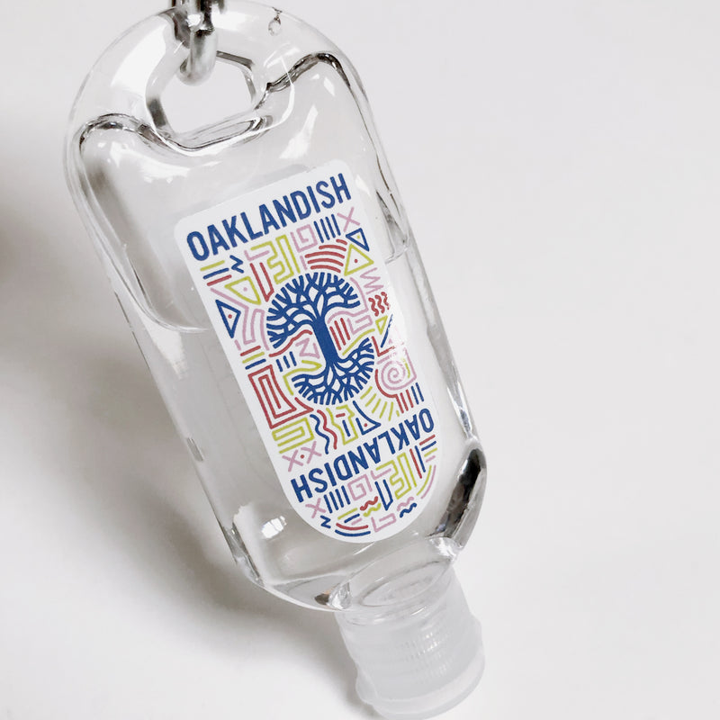 Close-up of travel-size hand sanitizer with Oaklandish logo and carabiner.