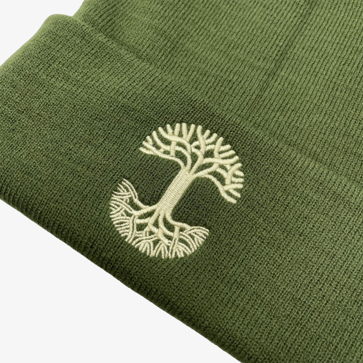 Close-up of yellow embroidered Oaklandish tree logo on the cuff of an olive green beanie.