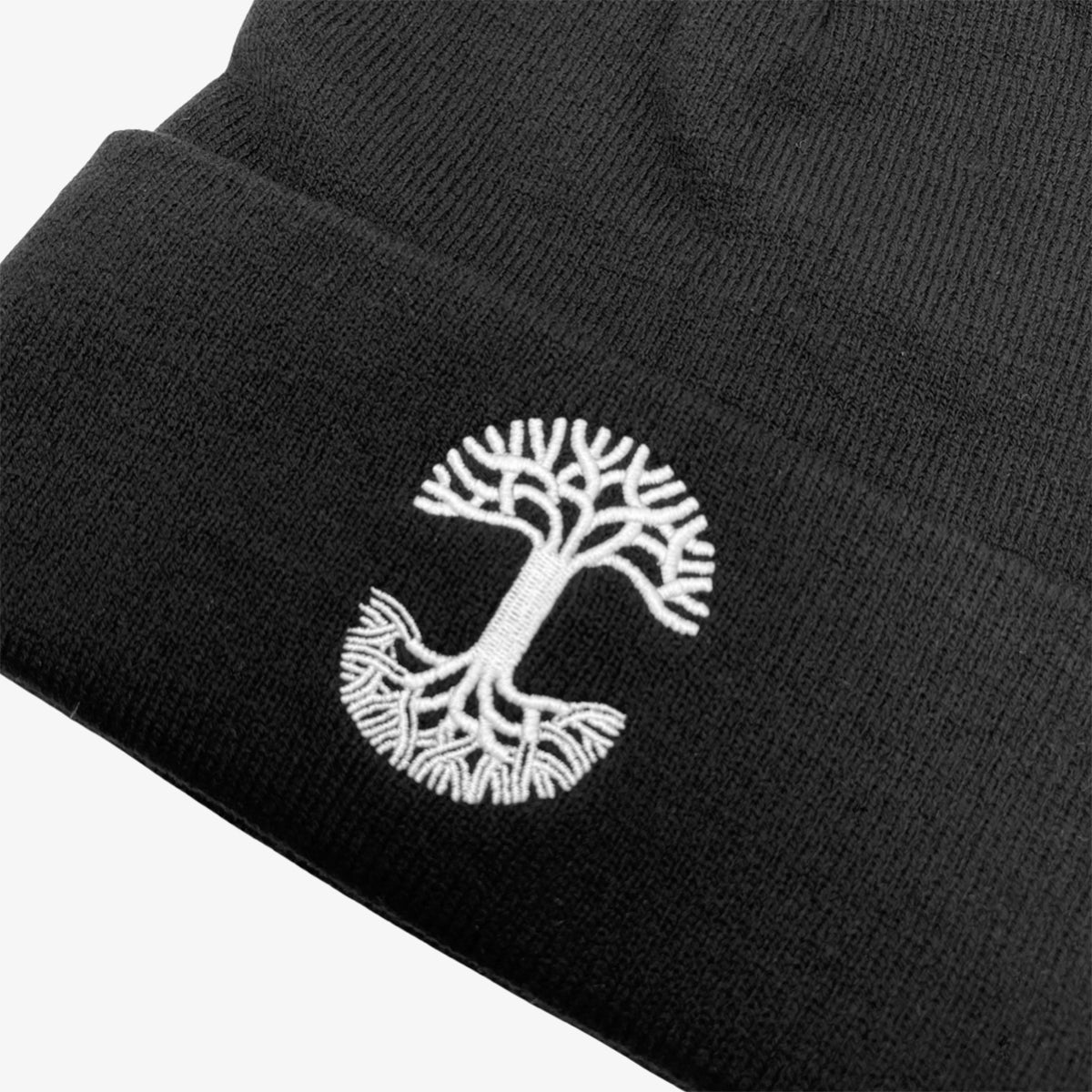 Close-up of white embroidered Oaklandish tree logo on the cuff of a black beanie.
