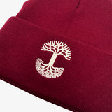 Close-up of white embroidered Oaklandish tree logo on the cuff of a burgundy beanie.