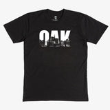 Black t-shirt with white capital letters spelling OAK, containing pictures of the Oakland skyline. 
