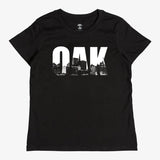 Close up of t-shirt graphic of white capital letters spelling OAK, containing pictures of the Oakland skyline.