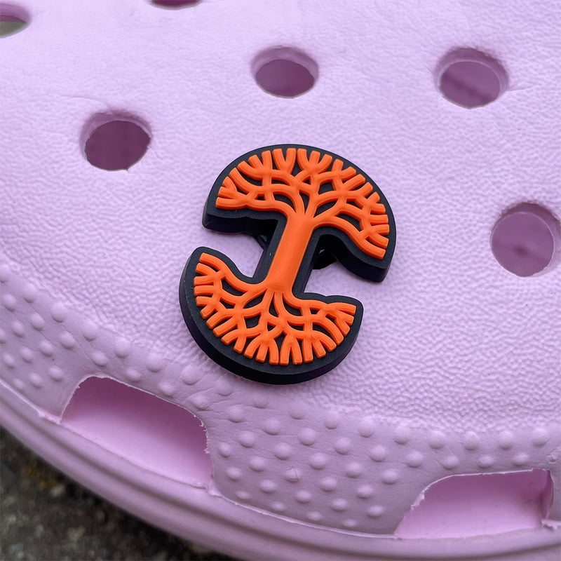 Orange and black Oaklandish tree logo shoe charm on pink croc clog.