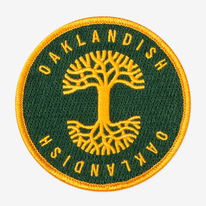 Round green circle patch with embroidered yellow Oaklandish tree logo in the center and Oaklandish wordmarks above and below.